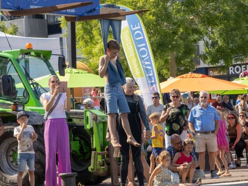 jongen die aan een spijkerbroek hangt boven het water, en publiek dat toekijkt