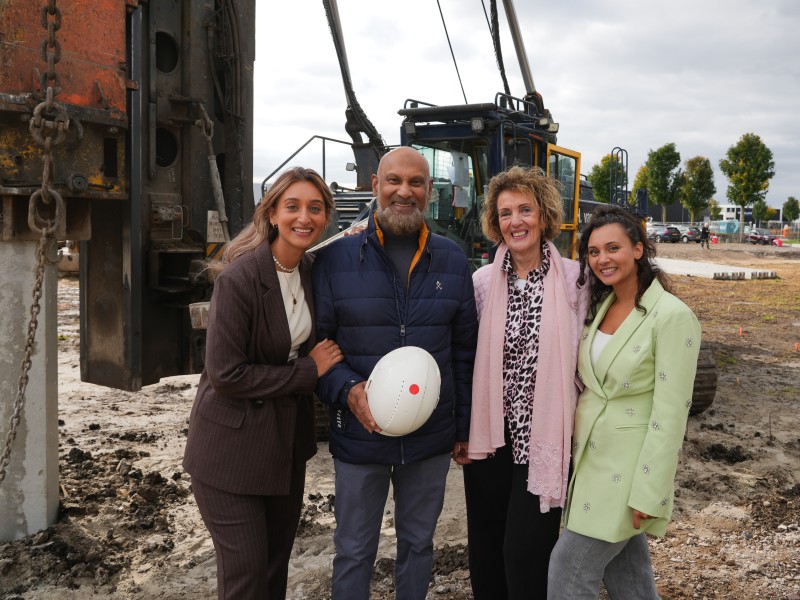 De familie Joeman bij een heipaal met helm in hand.