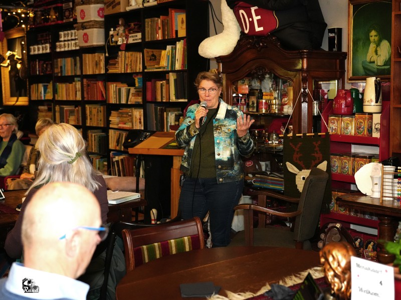 Mevrouw vertelt iets in een microfoon voor publiek.