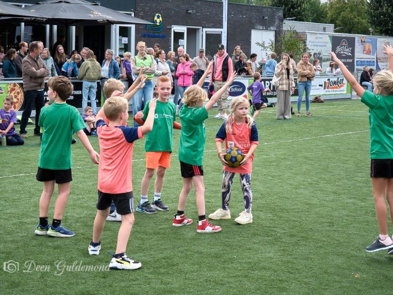 Kinderen korfballen buiten op een veld.