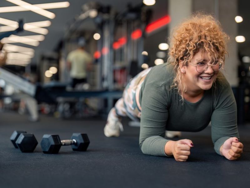 Een volwassenvrouw die de plankoefening doet in de sportschool