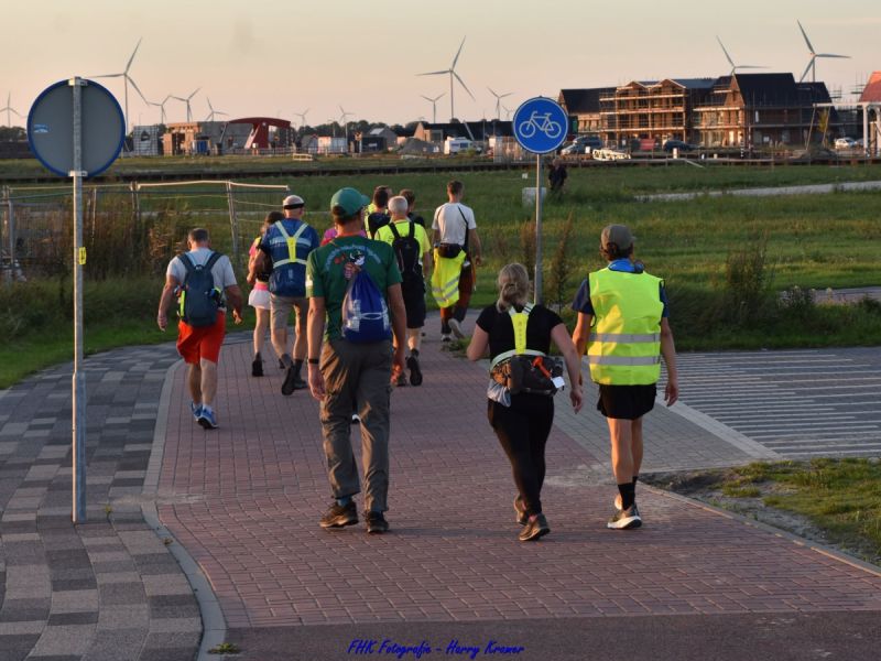 Wandelaars vanaf de rug die richting de sluis lopen in de Polderwijk