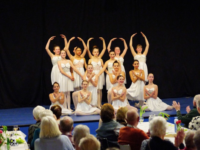 De balletgroeop op het podium voor de ouderen aan gedekte tafels