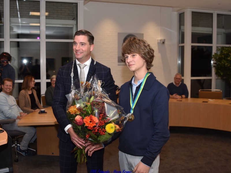 Job met burgemeester Harmsma met zijn lintje om en bloemen in de hand