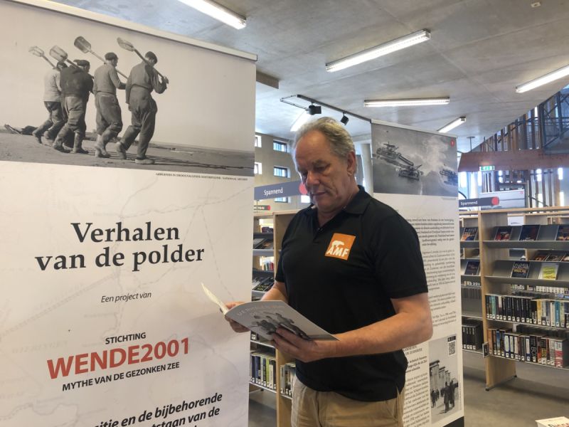 De expositie in de bibliotheek met ook de flyer daarbij die wordt vastgehouden  door AMF