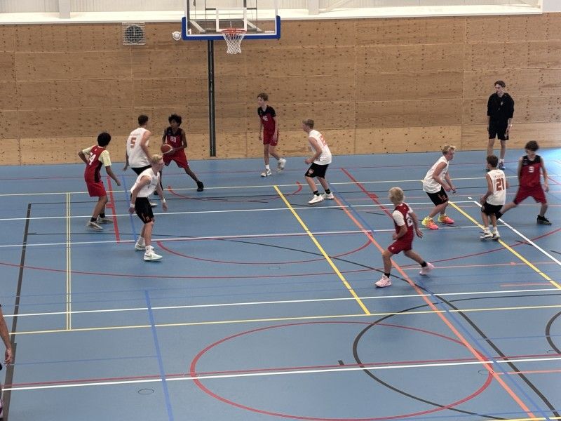 Basketballende jeugd in rode en witte tenues.