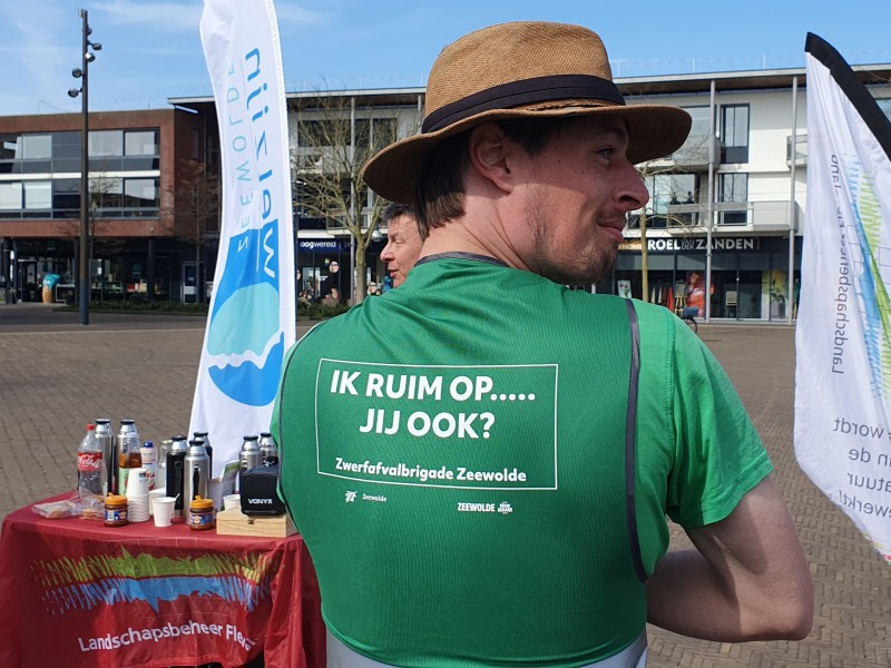 Man met groen hesjes staat op een plein.