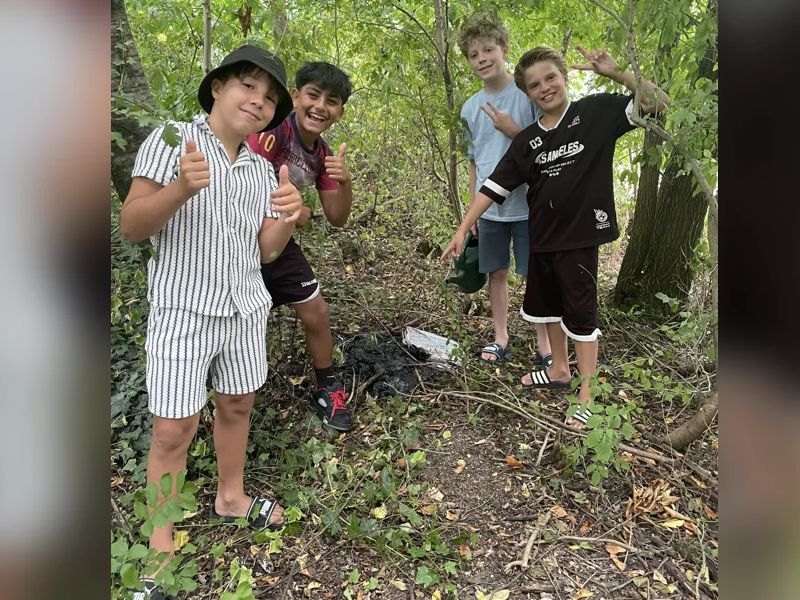 De brandplek en de vier jongens bij het gebluste vuur, van links naar rechts: Maxim, Mustafa, Noah en Senn.
