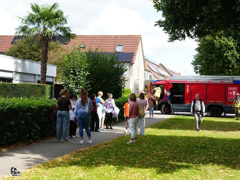 Brandweerauto naast gebouw met mensen buiten