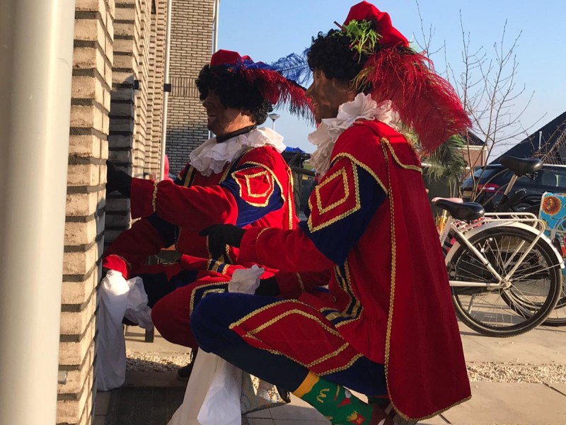 Pieten zitten gehurkt voor een deur of raam