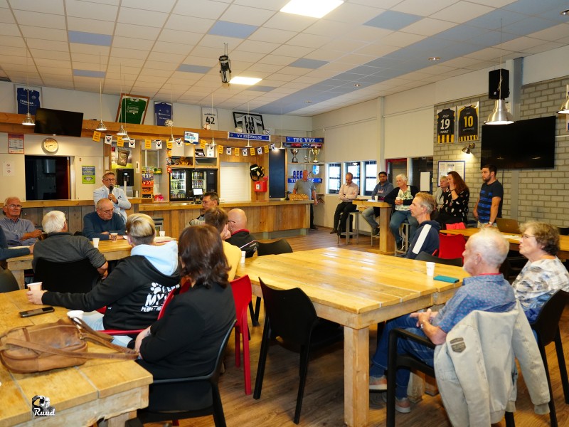 Mensen in een kantine die luisteren naar iemand met microfoon.