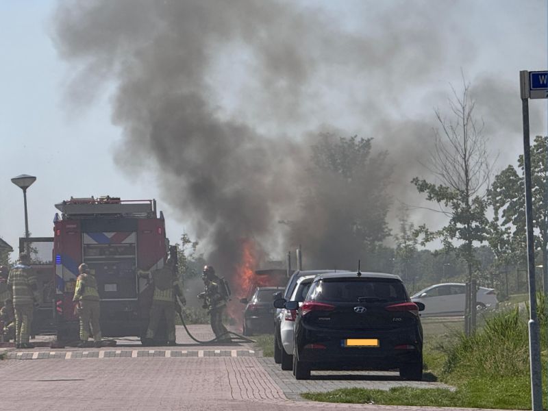 Brandende auto met brandweerauto ernaast