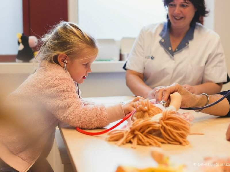 Kind met stethoscoop luistert naar haar pop.