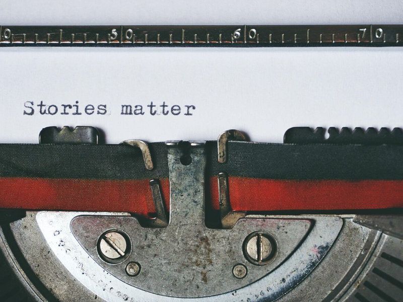 een ouderwetse typemachine met zwart rood typelint en het woord stories matter op een wit stuk papier