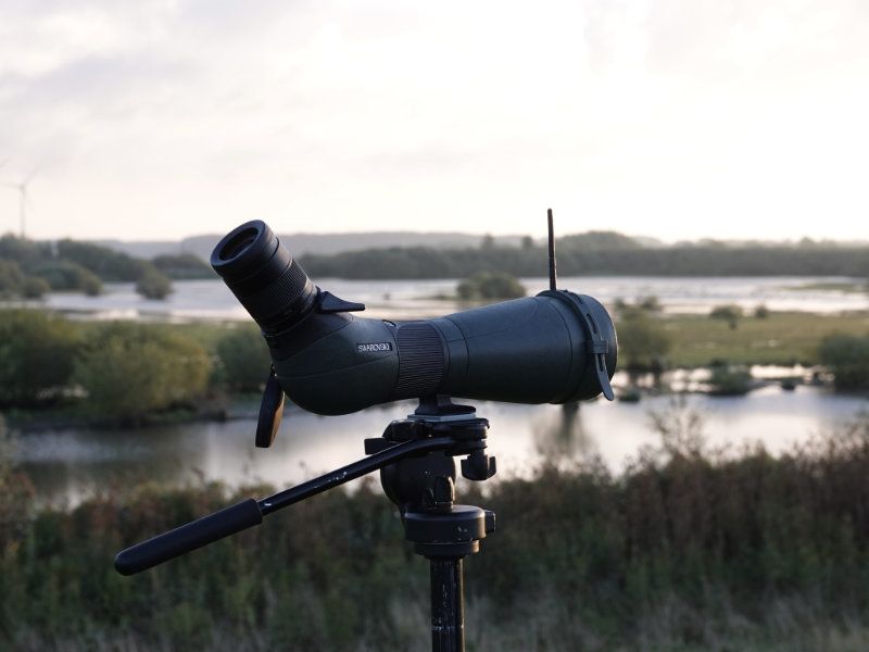 een telescoop die gericht staat op een natuurlandschap, bedoeld om vogels te kijken