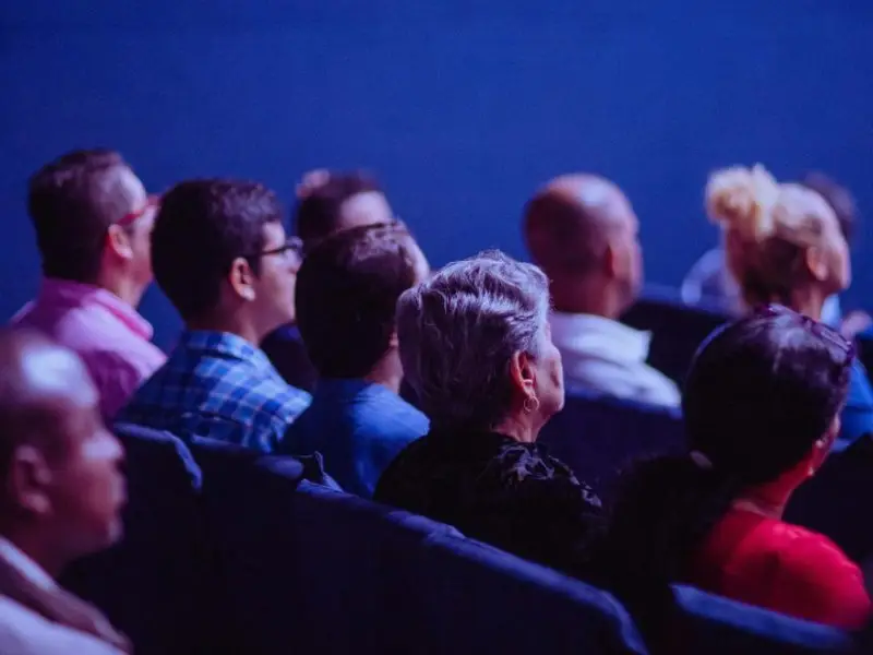 een groep mensen zitten op bioscoopstoelen en kijken vooruit
