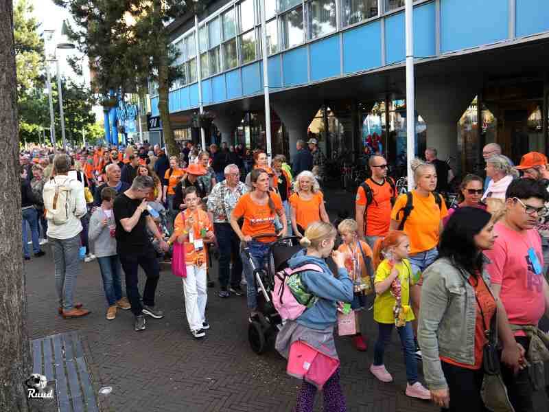 Vele wandelaars in overwegend oranje voor de albert Heijn