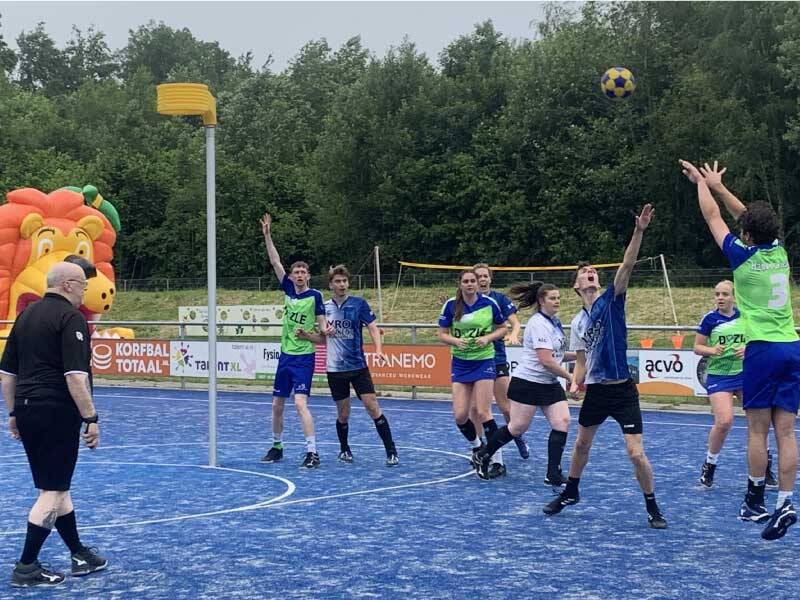 Kofballers op het veld met iemand van Wolderwijd die de bal naar de korf gooit