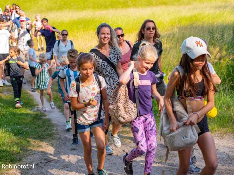 Een groep wandelende kinderen vanaf de dijk langs het gras, foto gemaakt door Robinotof