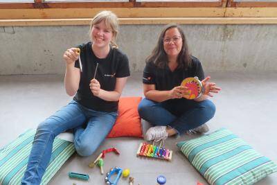 2 vrouwen die op de grond zitten met kinderspeelgoed