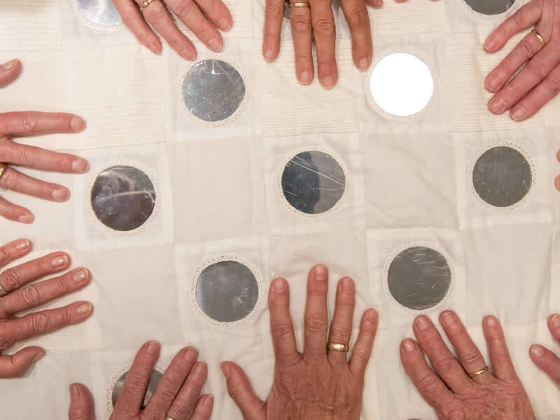 handen op het wandkleed wat men gezamelijk heeft gemaakt