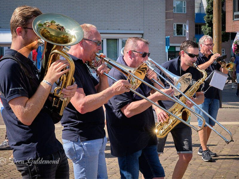 Foto van een dweilorkest die samen op een plein muziek maken.