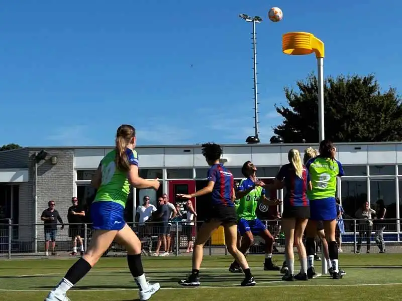 Kinderen op het korfbalveld met een scheids
