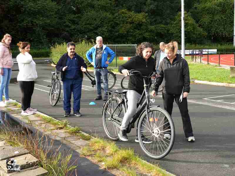 Mensen die aan het oefenen zijn met de fiets en mensen die er om heen staan op de atletiekbaan