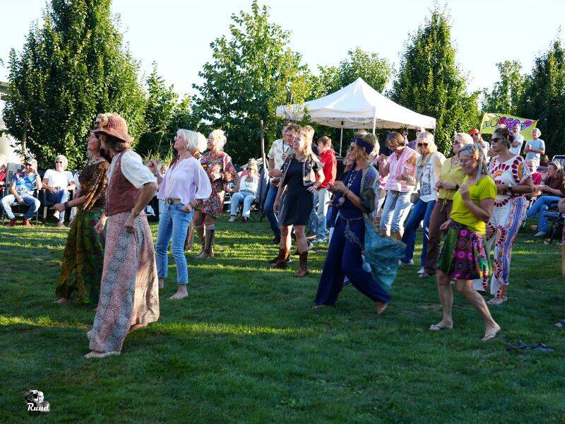 Mensen verkleed in felgekleurde kleding dansen met elkaar.