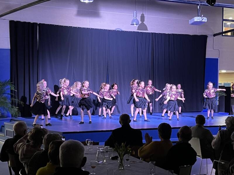 op een groot podium staan jonge kinderen te dansen, ze geven een voorstelling