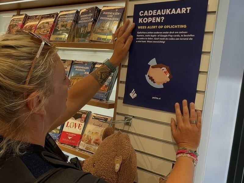 Een dame bij de poster over cadeaukaartfraude