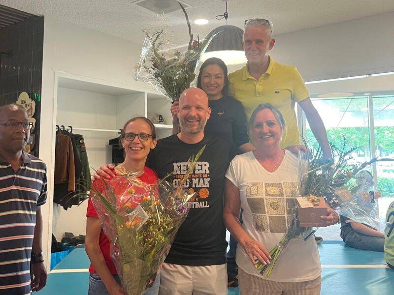 Mensen op een foto voor en achter elkaar met bloemen in hun hand.