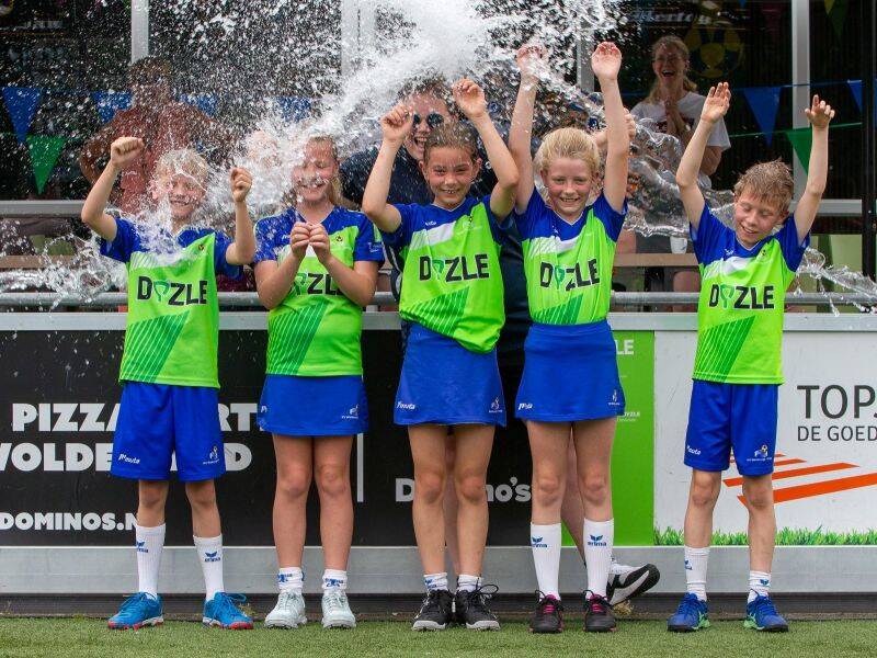 kinderen met groen en blauwe sportoutfit die onder een waterstraal staan