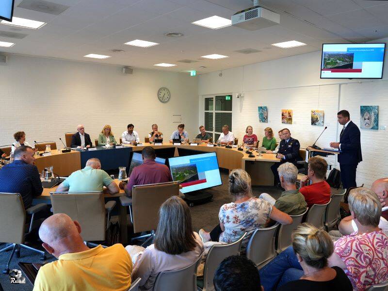 Raadszaal met publiek, raadsleden en ook de burgemeester die spreekt