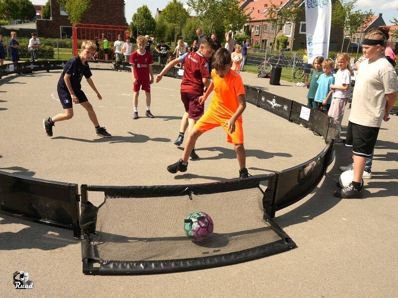 Voetballende kinderen op straat met publiek