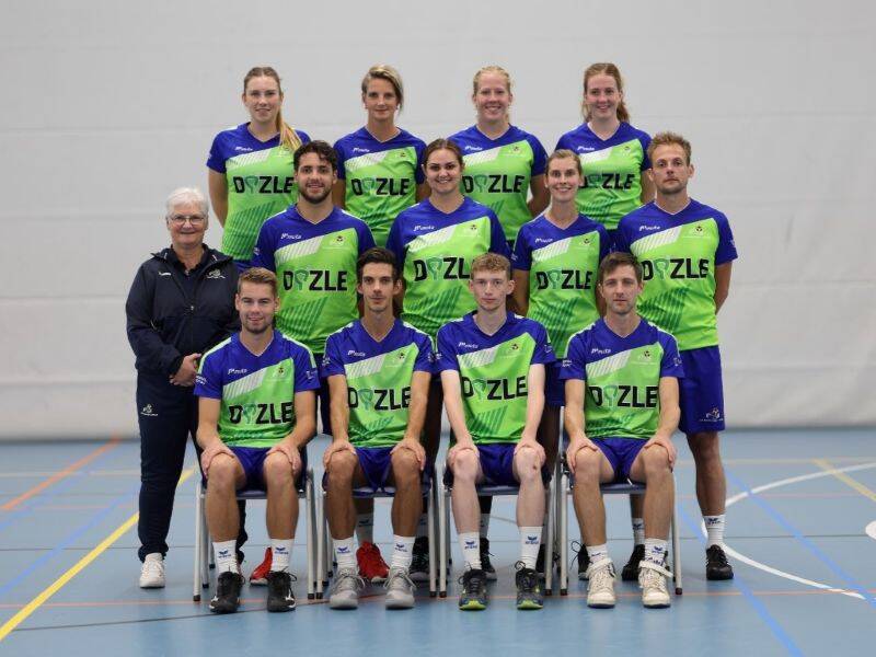 Korfbalteam met groene shirts in sportzaal met blauwe vloer.