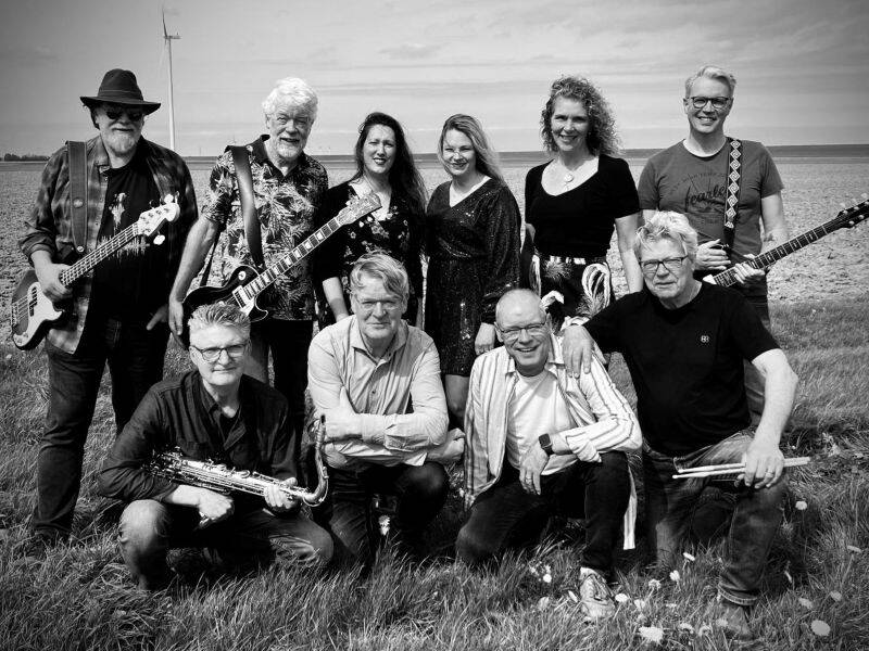 zwart wit foto van een groep mensen met muziekinstrumenten in een weiland