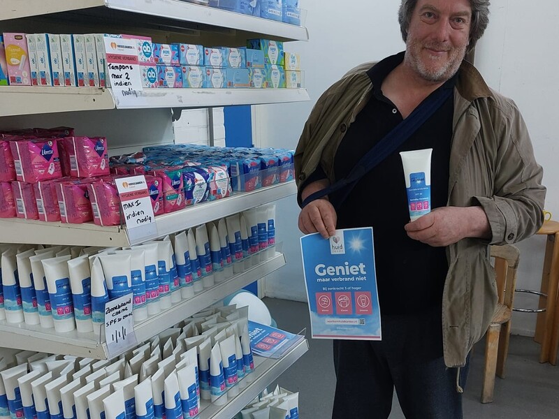 meneer met poster en flacon zonnebrand bij het schap 