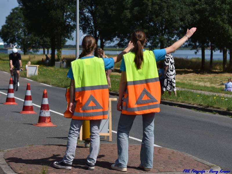 2 evenementenverkeersregelaars vanaf de rug die de weg wijzen naar een wielrenner 