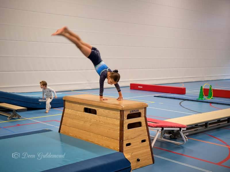 Sporthal met turntoestellen met een meisje met de handstand op de kast